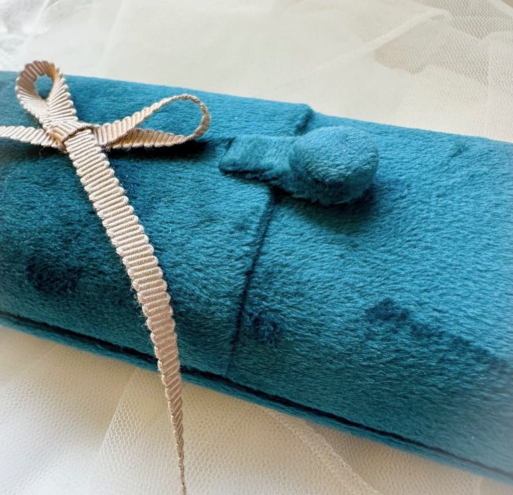 Blue folded velvet box with a beige ribbon on a white background
