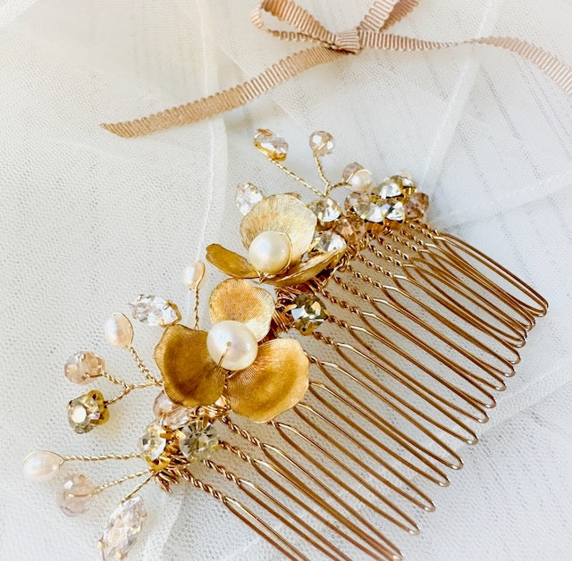 Gold hair comb with floral and pearl details on a white background