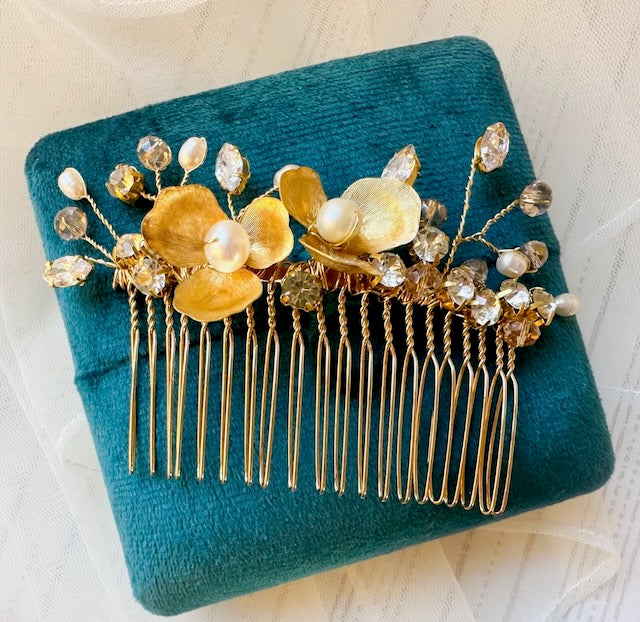 Gold hair comb with floral and bead details on a teal fabric background