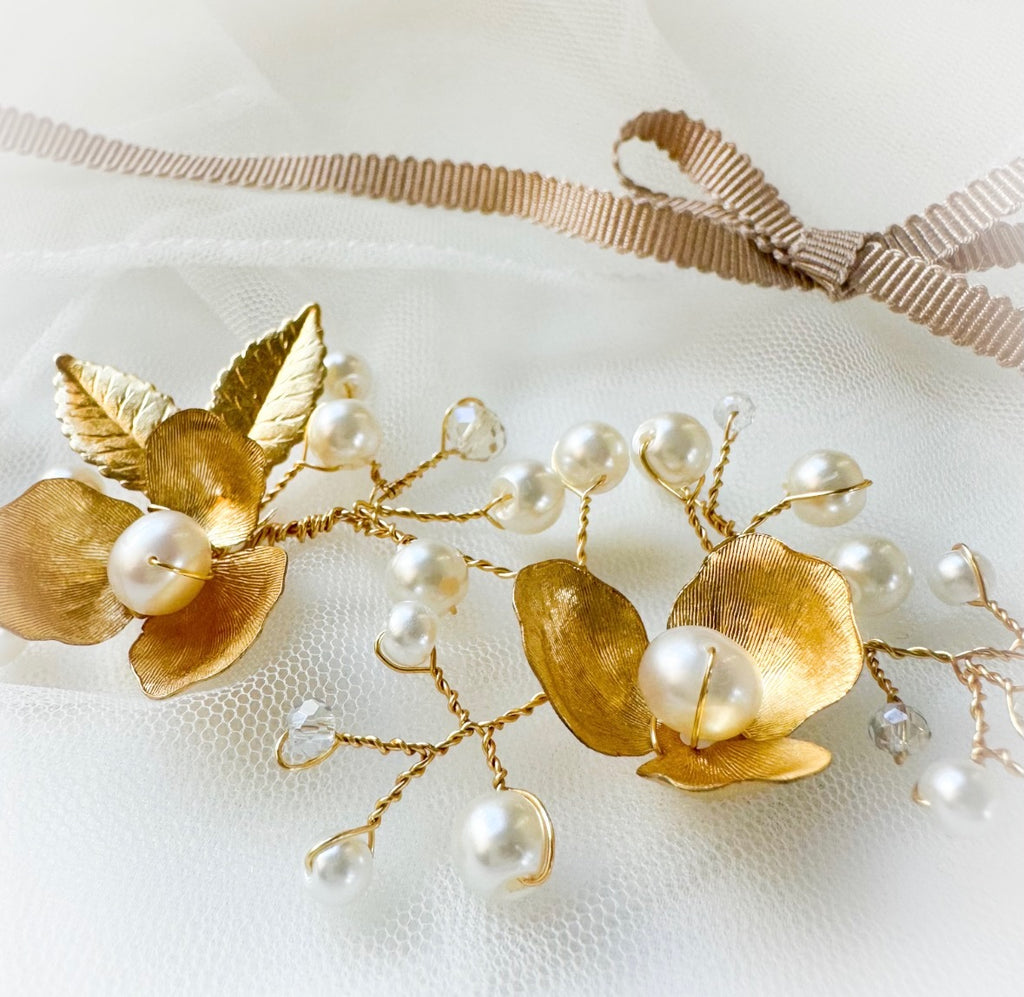 Gold bridal hairvine with leaves and pearls on a white background