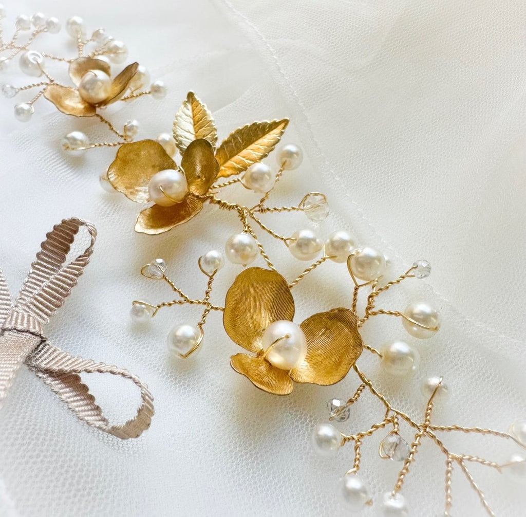 Gold floral hairvine with pearls on a white fabric background