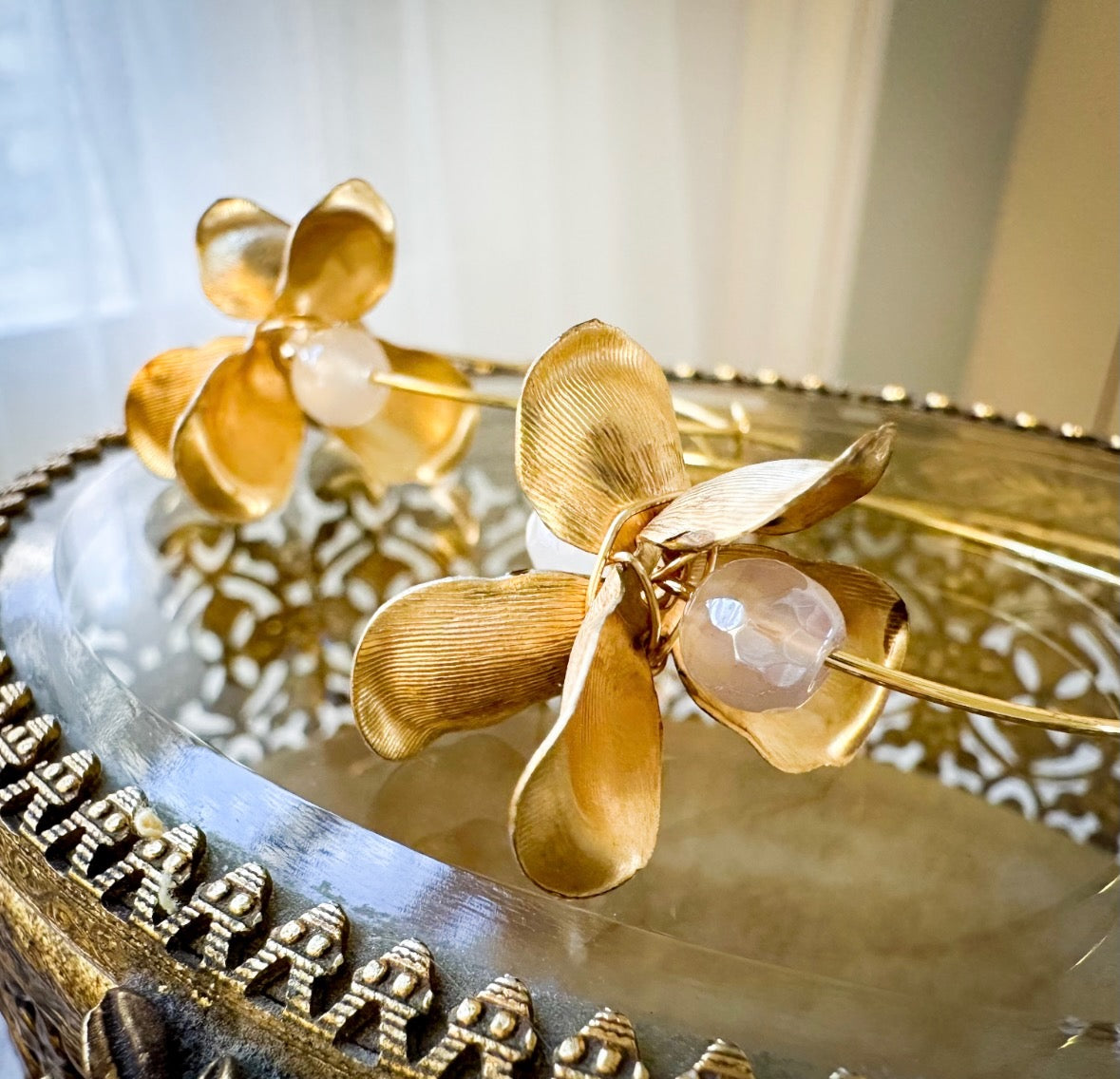 Gold flower-shaped earrings on a vintage jewelry box.