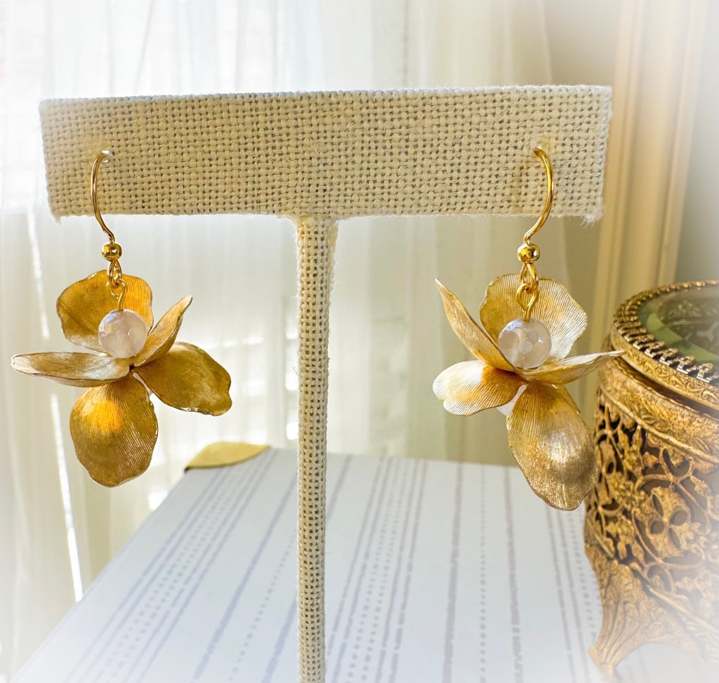 Gold flower-shaped earrings on a lampshade with a blurred background
