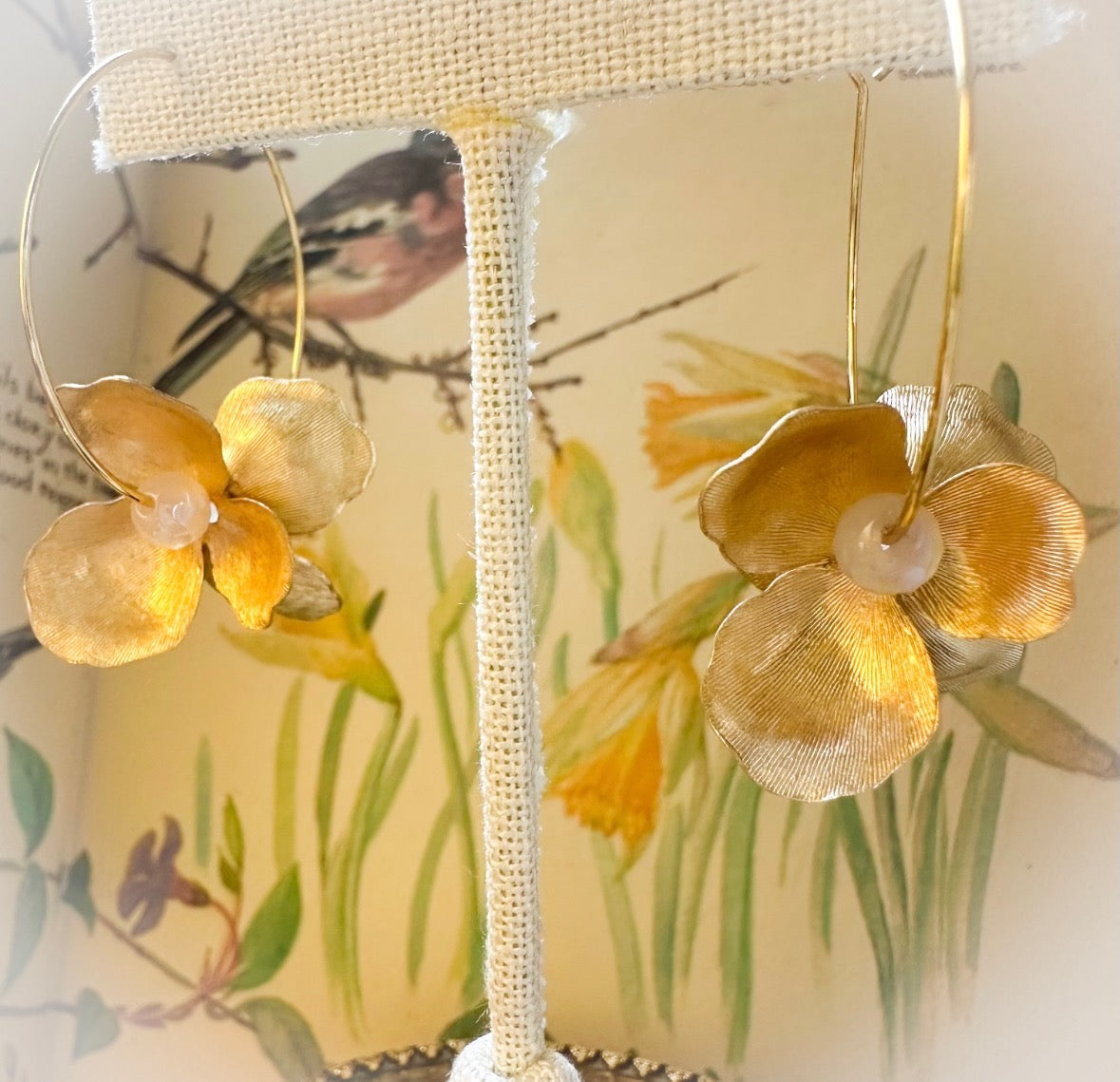 Gold floral earrings on a decorative box with floral design