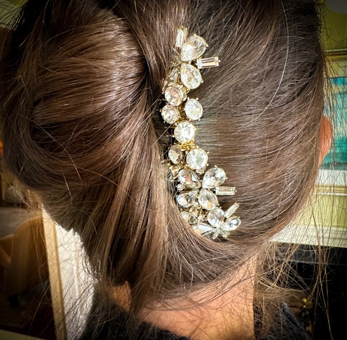 Close-up of a person's hair with a decorative hairpin featuring crystals.