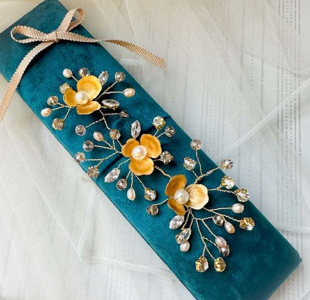 Decorative hair clip with floral design and crystals on a teal background