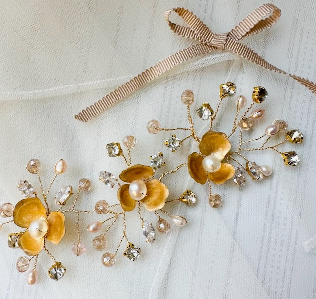 Decorative hair pins with gold flowers and pearls on a white background